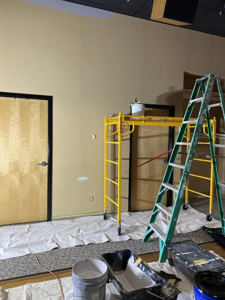 Professional painters using scaffolding to paint interior commercial high walls.