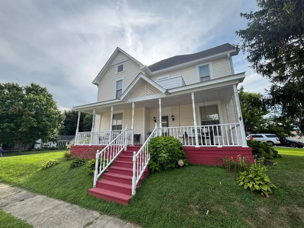 White farmhouse-style home with a red front porch after exterior painting in Brownsburg, IN