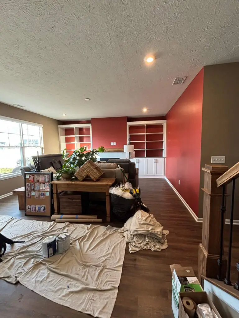 Interior painting project in progress in a Brownsburg, IN home featuring a red accent wall with drop cloths covering the floor
