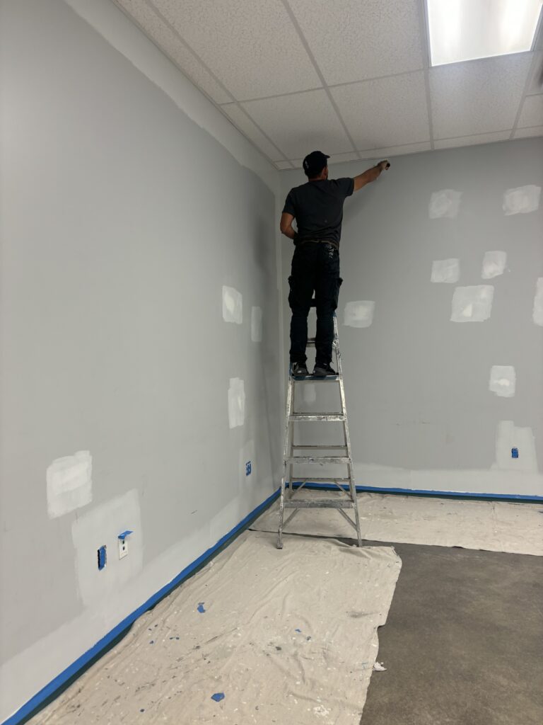 A painter on a ladder working on painting interior